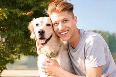 Portrait of happy owner with cute Golden Retriever dog outdoors on sunny day