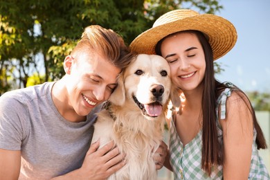 Photo of Happy couple with cute Golden Retriever dog outdoors on sunny day