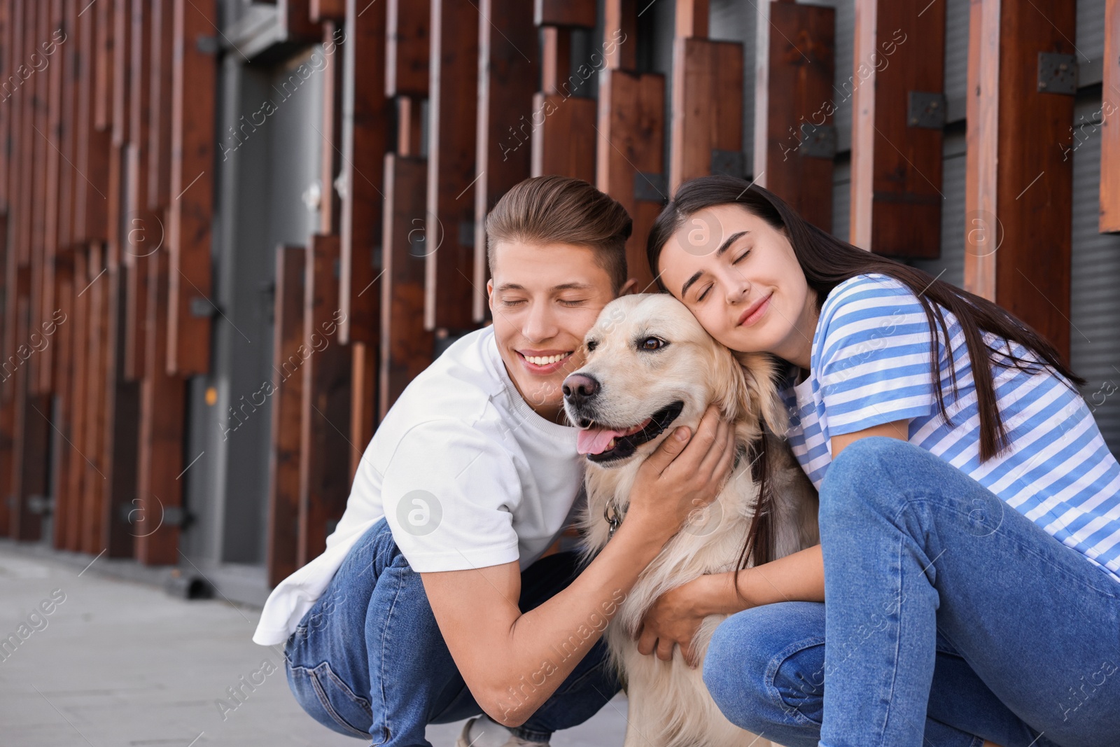 Photo of Happy couple with cute Golden Retriever dog outdoors. Space for text