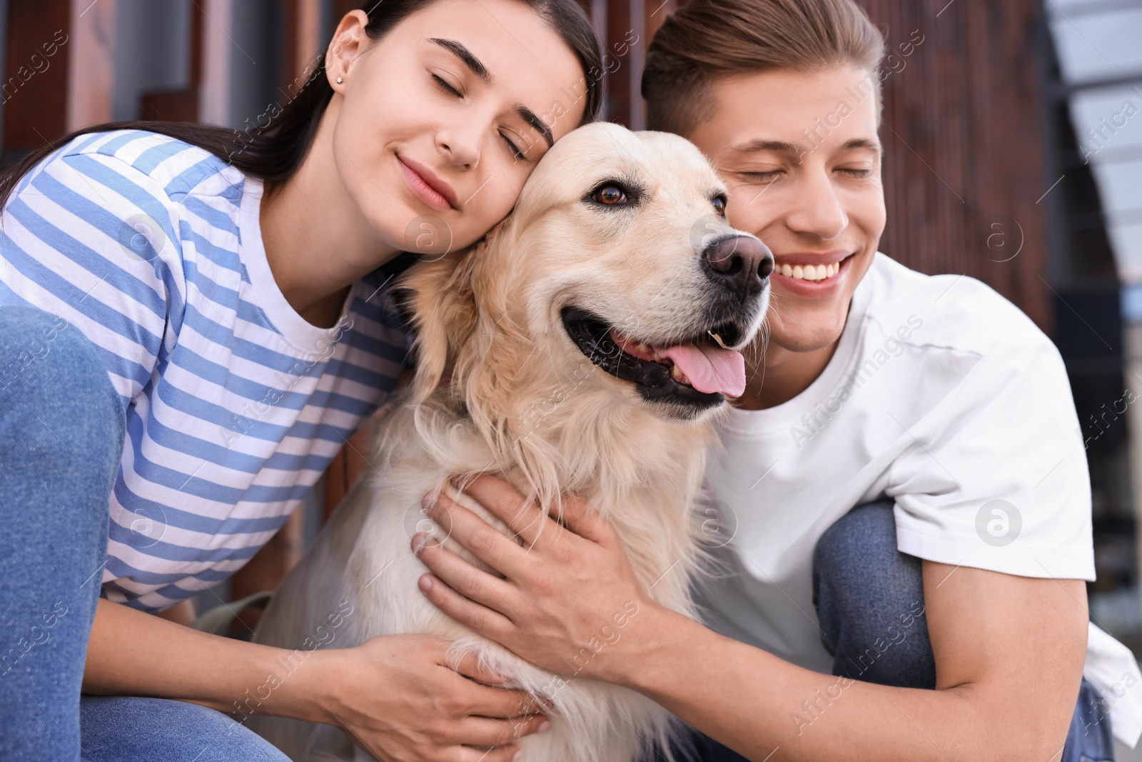 Photo of Happy couple with cute Golden Retriever dog outdoors