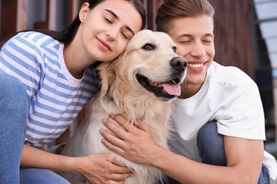 Photo of Happy couple with cute Golden Retriever dog outdoors