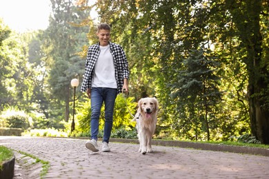 Photo of Happy owner walking with cute Golden Retriever dog outdoors, low angle view