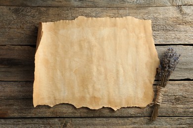 Sheet of old parchment paper and lavender flowers on wooden table, top view