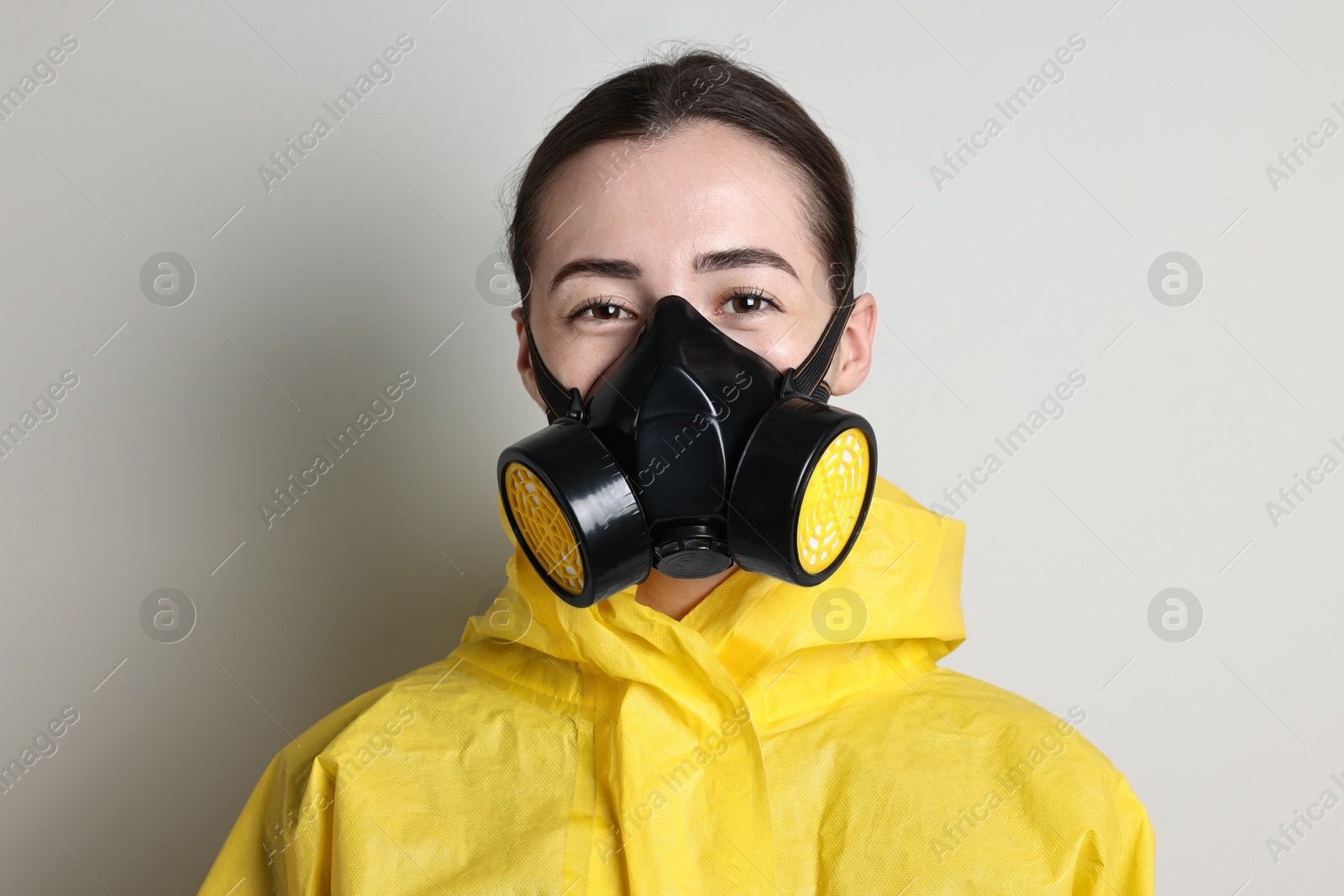 Photo of Worker in respirator and protective suit on grey background