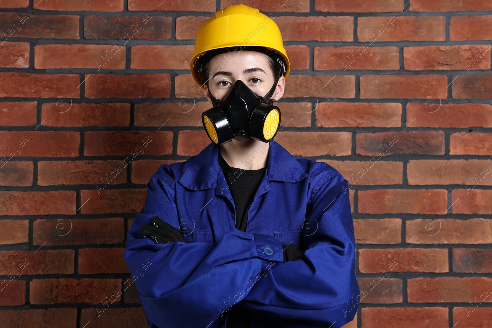 Photo of Worker in respirator and helmet near brick wall