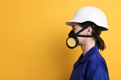 Photo of Worker in respirator and helmet on orange background, space for text