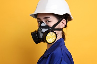 Photo of Worker in respirator and helmet on orange background