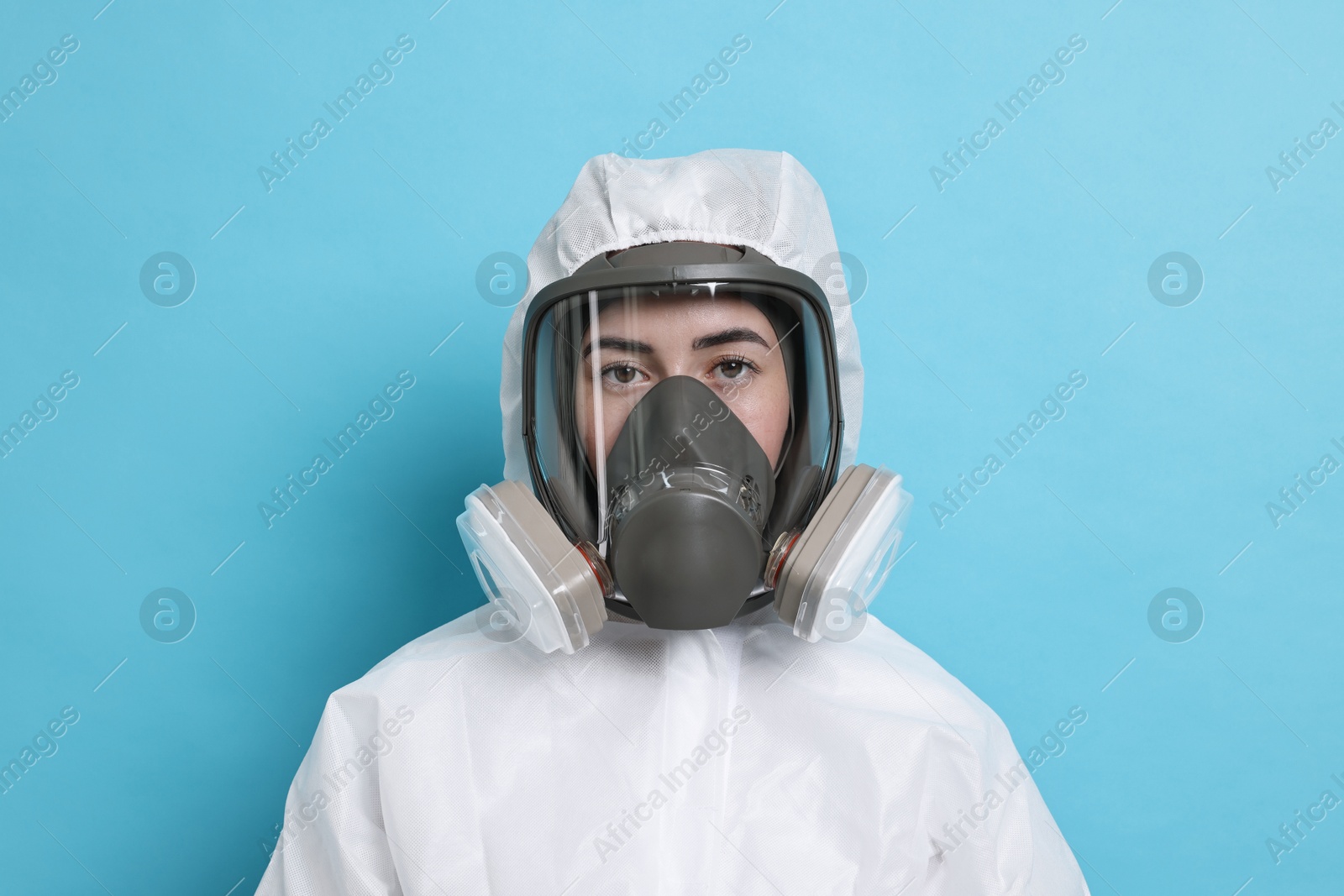 Photo of Worker in respirator and protective suit on light blue background