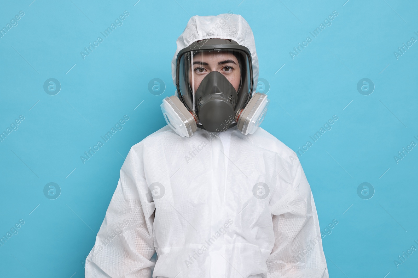 Photo of Worker in respirator and protective suit on light blue background