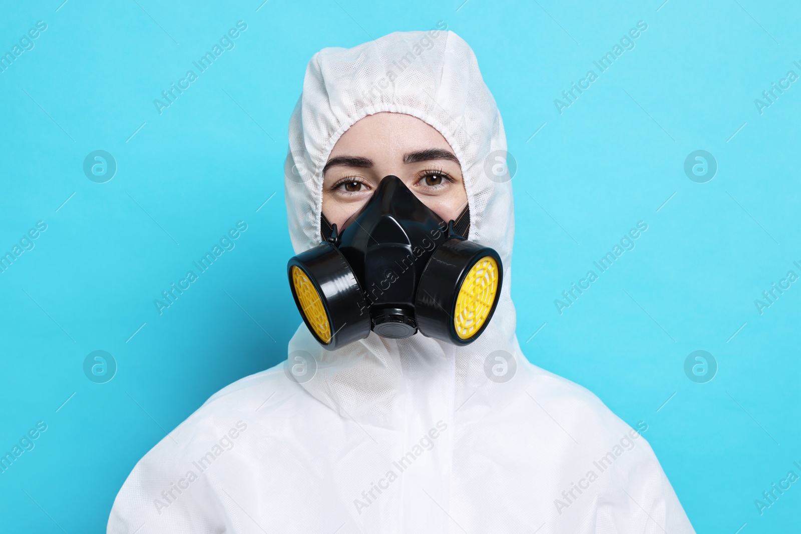 Photo of Worker in respirator and protective suit on light blue background