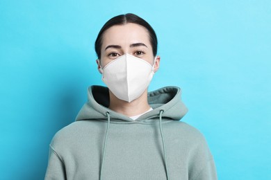 Photo of Woman in respirator mask on light blue background