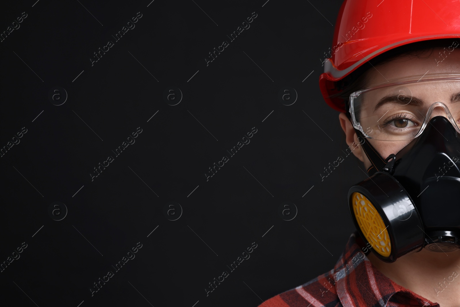 Photo of Woman in respirator, protective glasses and helmet on black background, space for text