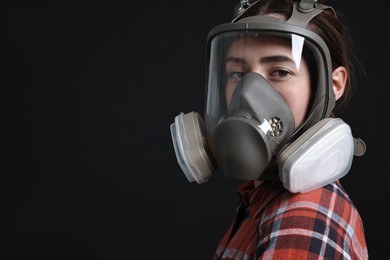 Photo of Woman in respirator mask on black background, space for text