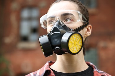 Photo of Woman in respirator and protective glasses outdoors