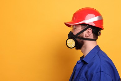 Photo of Man in respirator mask and hard hat on yellow background. Space for text