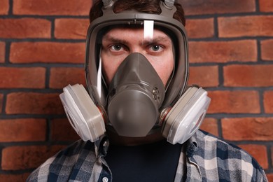 Photo of Man in respirator mask near red brick wall