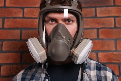 Man in respirator mask near red brick wall