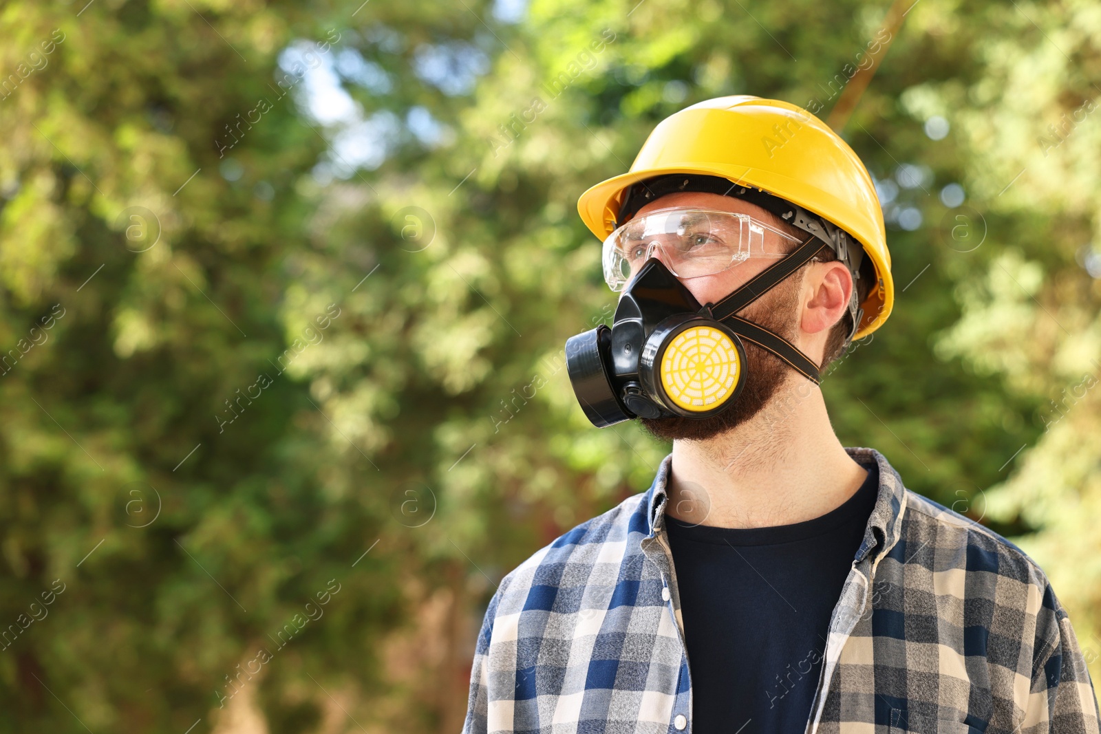 Photo of Man in respirator mask and hard hat outdoors, space for text. Safety equipment