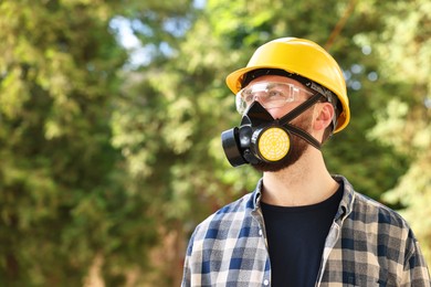 Photo of Man in respirator mask and hard hat outdoors, space for text. Safety equipment