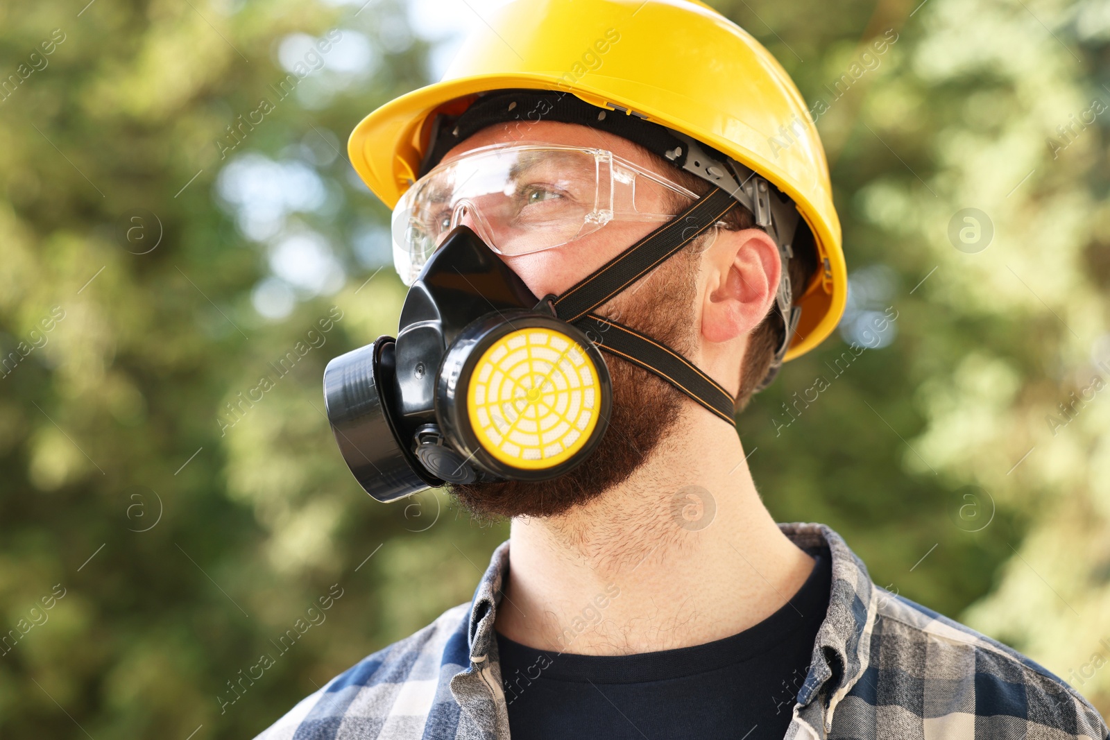 Photo of Man in respirator mask and hard hat outdoors. Safety equipment