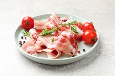 Photo of Slices of raw bacon, spices and tomatoes on light grey table