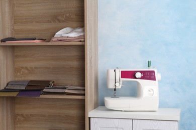 White sewing machine on nightstand near light blue wall indoors