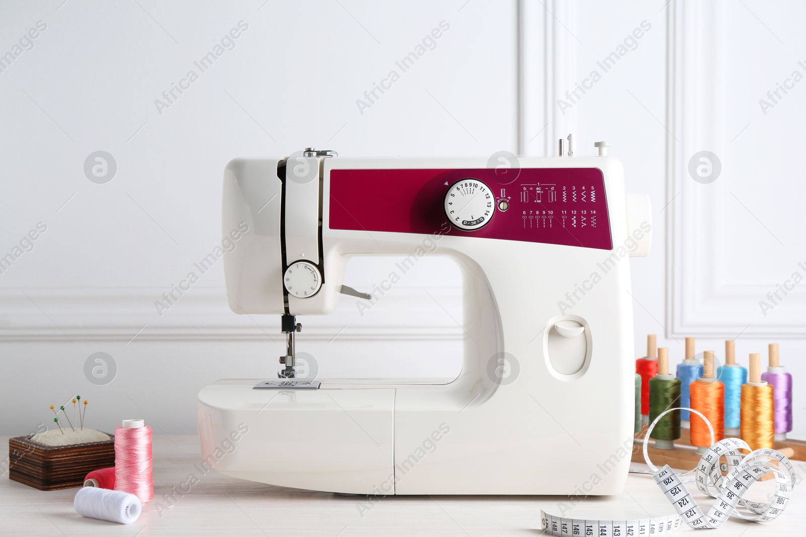 Photo of Sewing machine and craft accessories on white wooden table indoors