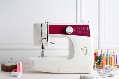 Sewing machine and craft accessories on white wooden table indoors