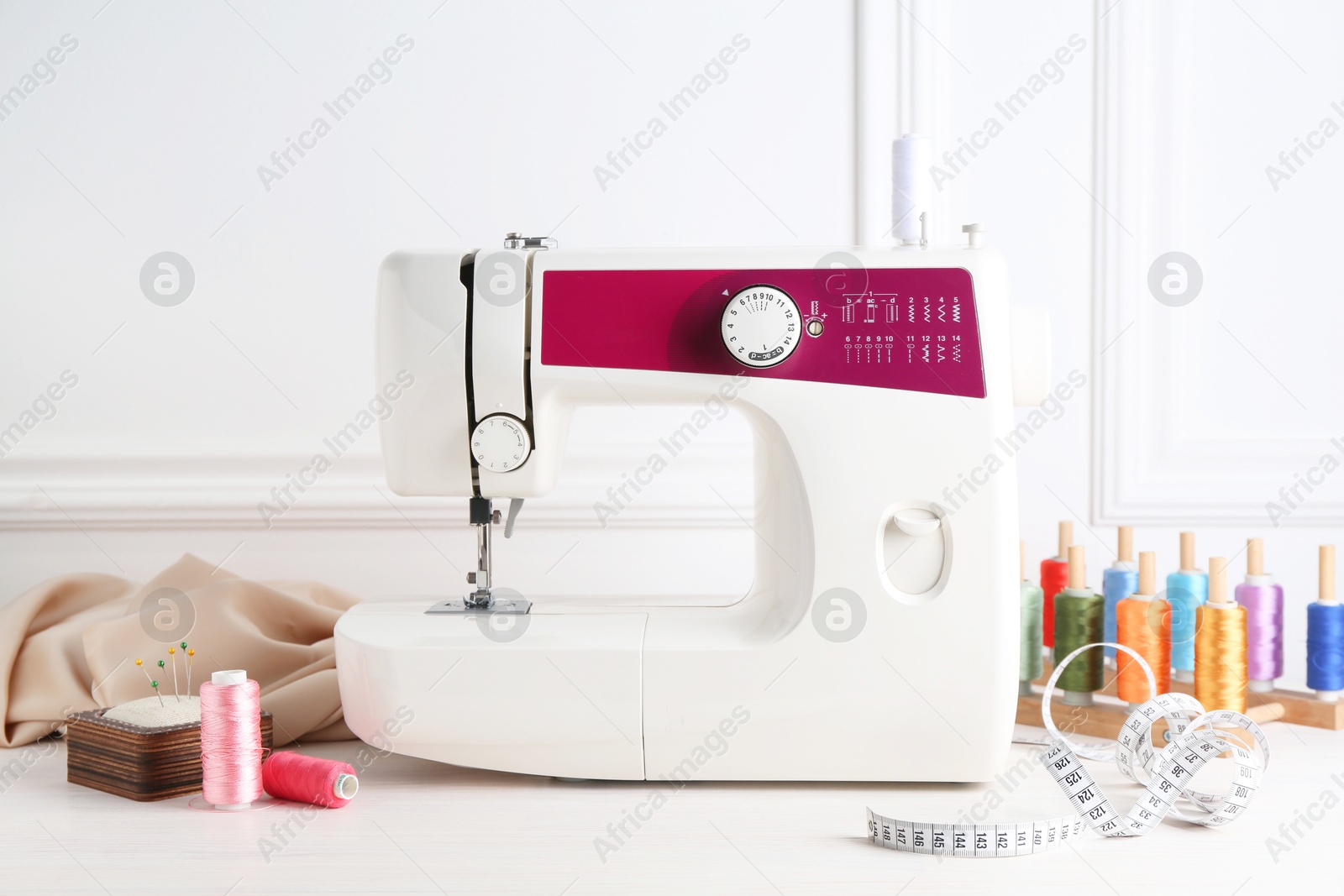 Photo of Sewing machine and craft accessories on white wooden table indoors