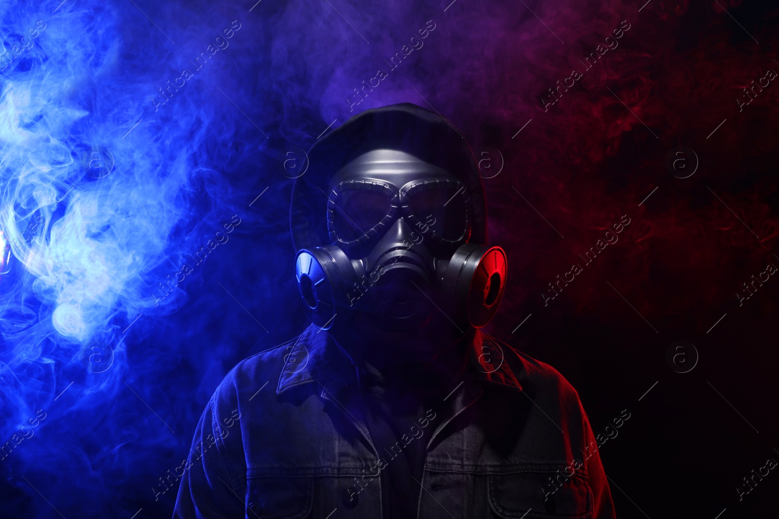 Photo of Man wearing gas mask in color lights and smoke on black background