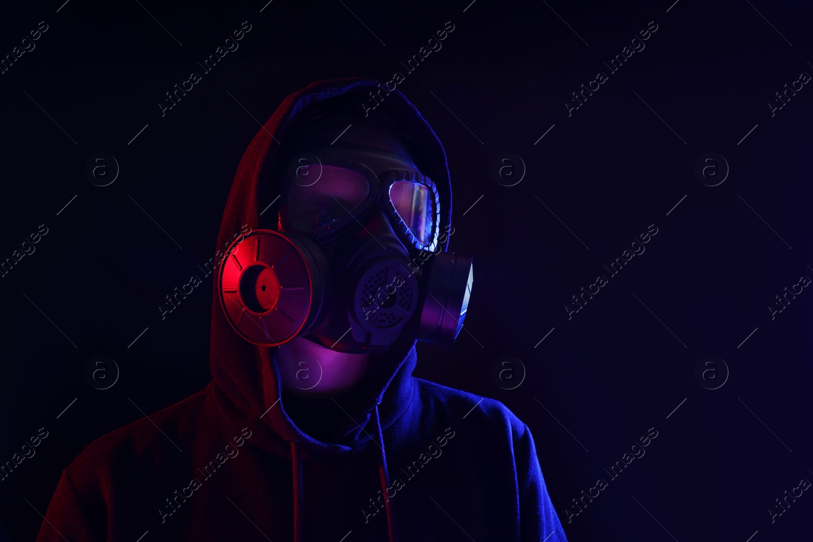 Photo of Man wearing gas mask in color lights on black background. Space for text