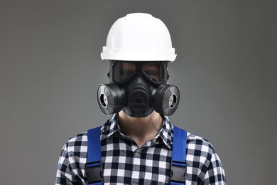 Photo of Worker in gas mask and helmet on grey background