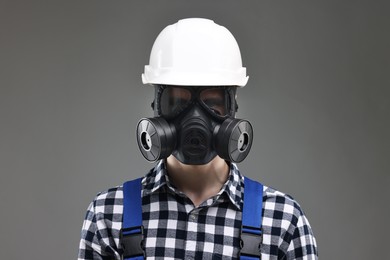 Worker in gas mask and helmet on grey background