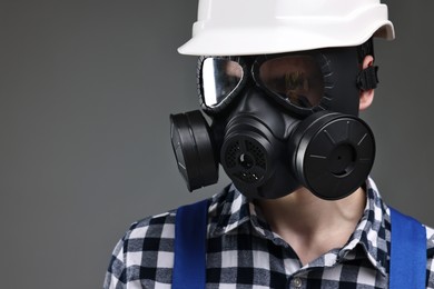 Photo of Worker in gas mask and helmet on grey background. Space for text