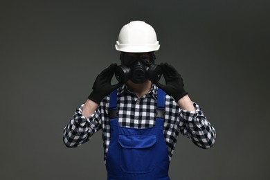 Worker in gas mask and helmet on grey background