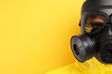 Worker in gas mask on yellow background, closeup. Space for text