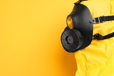 Photo of Worker in gas mask on yellow background, closeup. Space for text