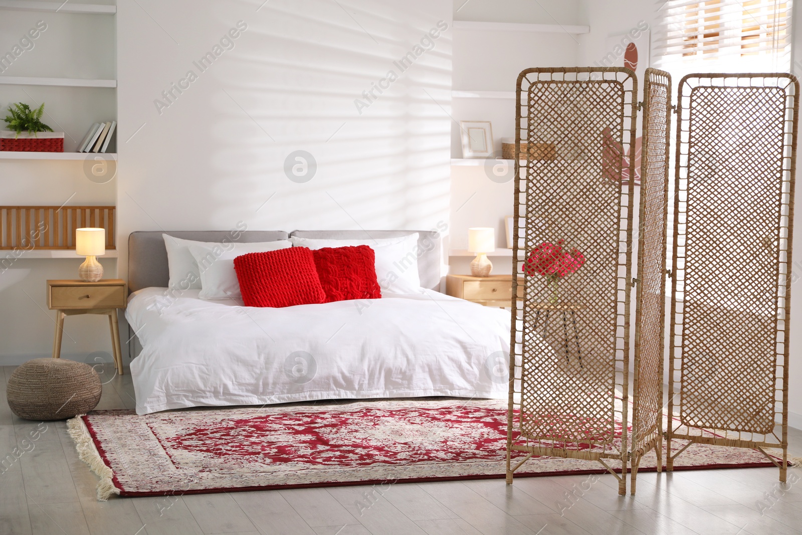 Photo of Beautiful folding screen, carpet and large bed in bedroom. Interior design