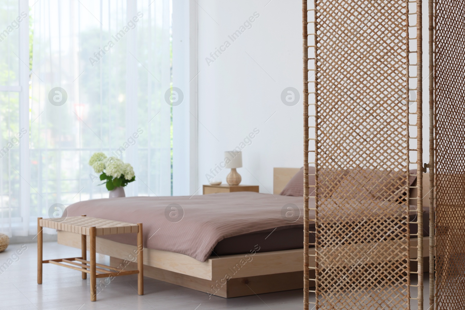 Photo of Folding screen, comfortable bed, ottoman and bedside table in room