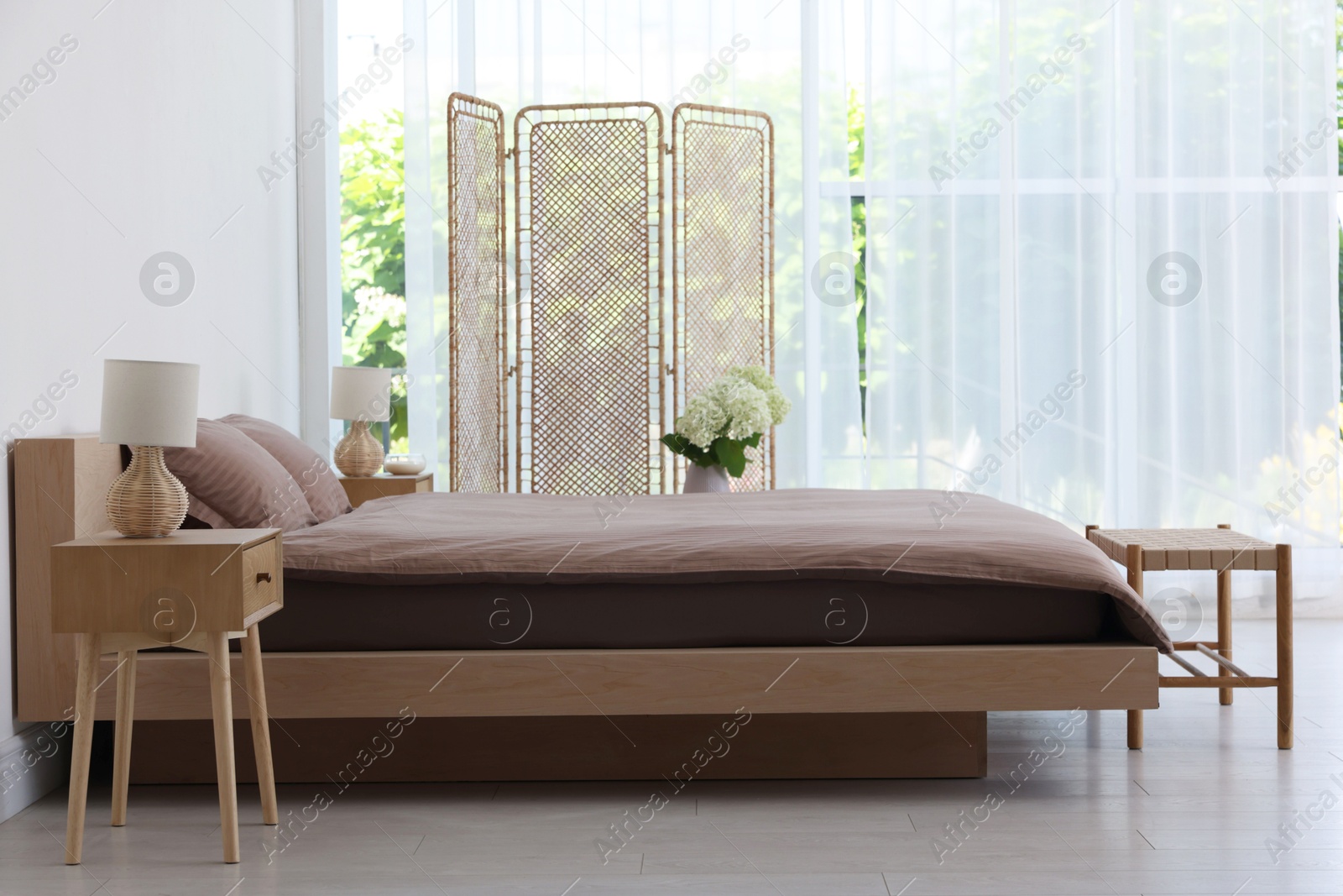 Photo of Folding screen, comfortable bed, ottoman and bedside tables in room