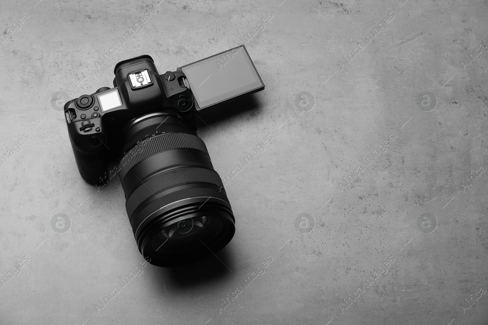 Photo of Modern photo camera on grey table, space for text. Photographer's equipment