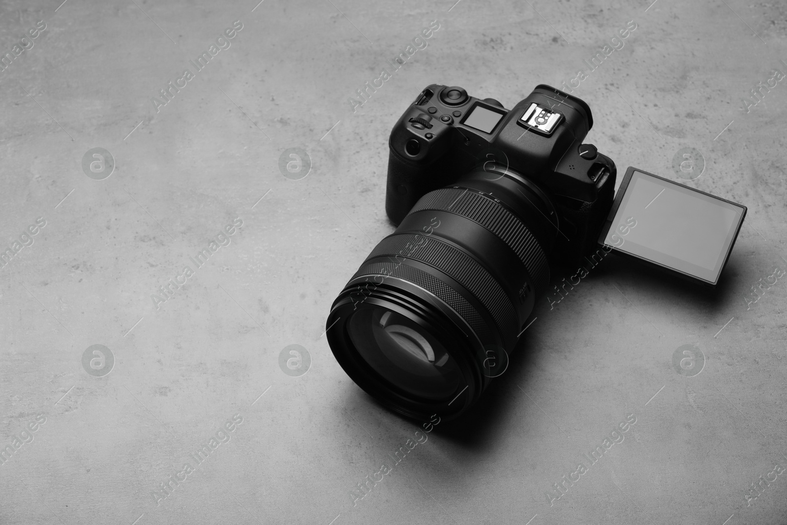 Photo of Modern photo camera on grey table, space for text. Photographer's equipment