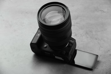 Modern photo camera on grey table. Photographer's equipment