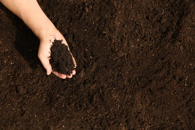 Woman holding pile of soil outdoors, top view. Space for text