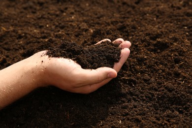 Woman holding pile of soil outdoors, closeup