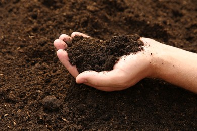 Photo of Woman holding pile of soil outdoors, closeup