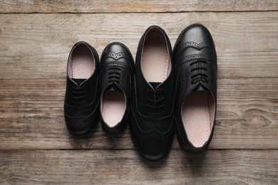 Photo of Big and small shoes on wooden table, top view