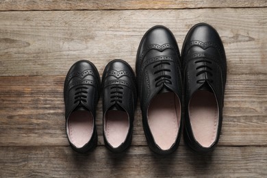 Big and small shoes on wooden table, top view