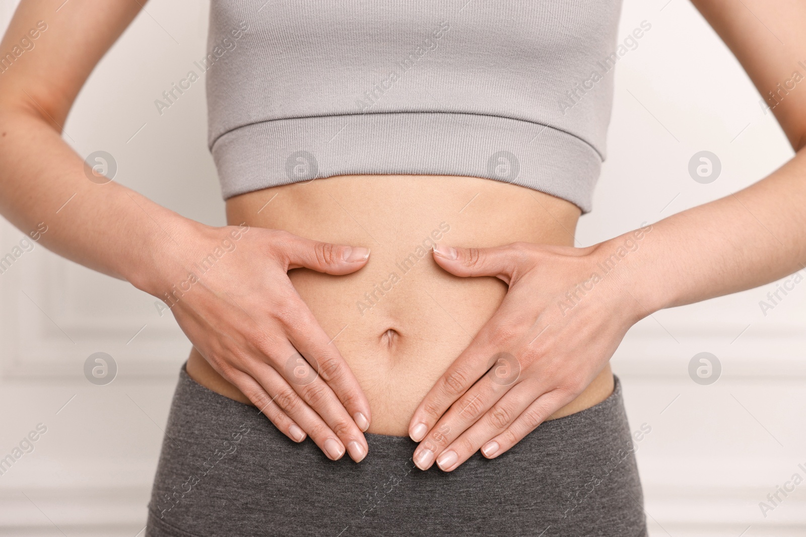 Photo of Healthy digestion. Woman touching her belly indoors, closeup