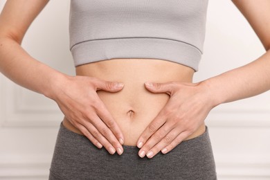 Photo of Healthy digestion. Woman touching her belly indoors, closeup